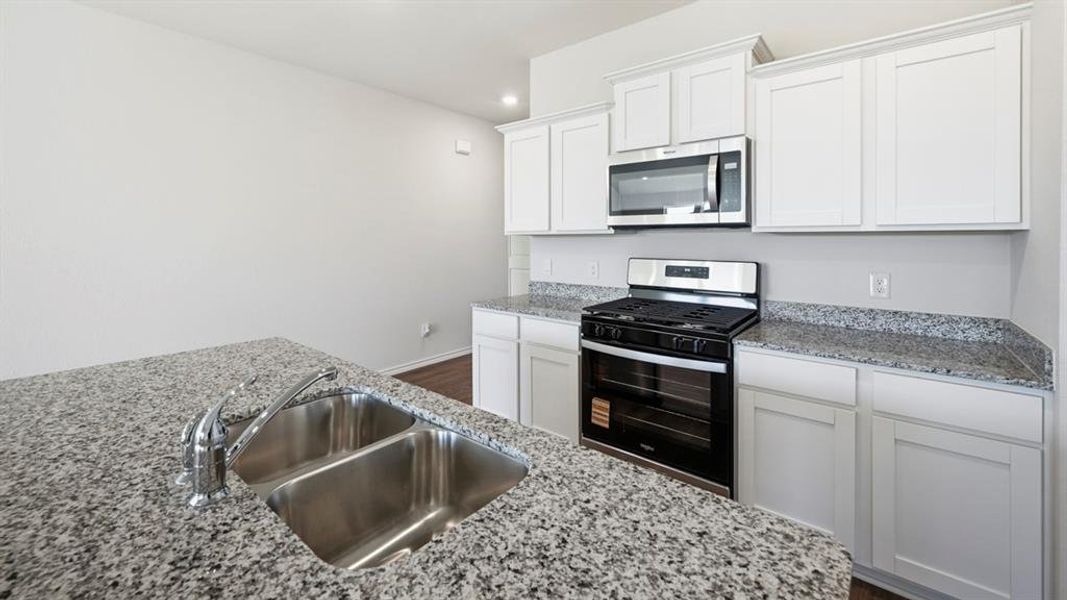 Kitchen featuring stainless steel appliances, white cabinets, light stone countertops, recessed lighting, and dark wood-type flooring