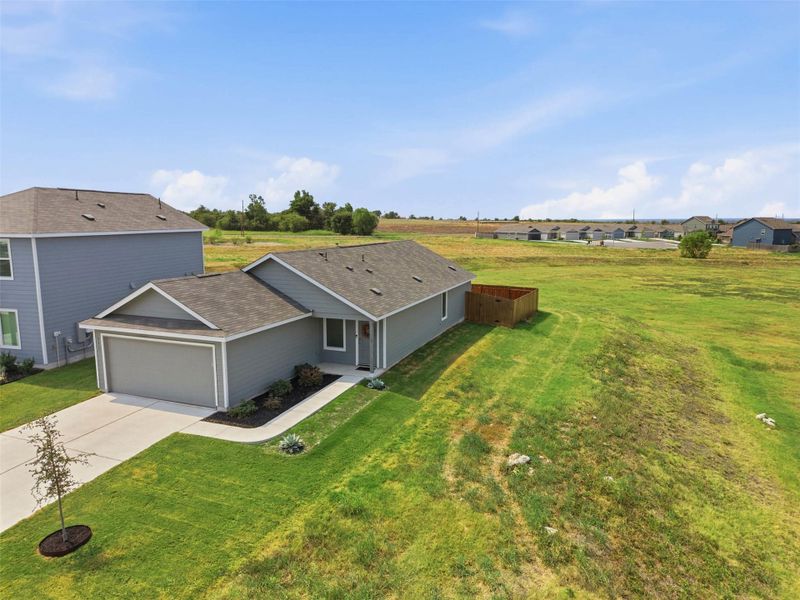 An elevated perspective captures the modern facade, concrete driveway, and sprawling surrounding green space.
