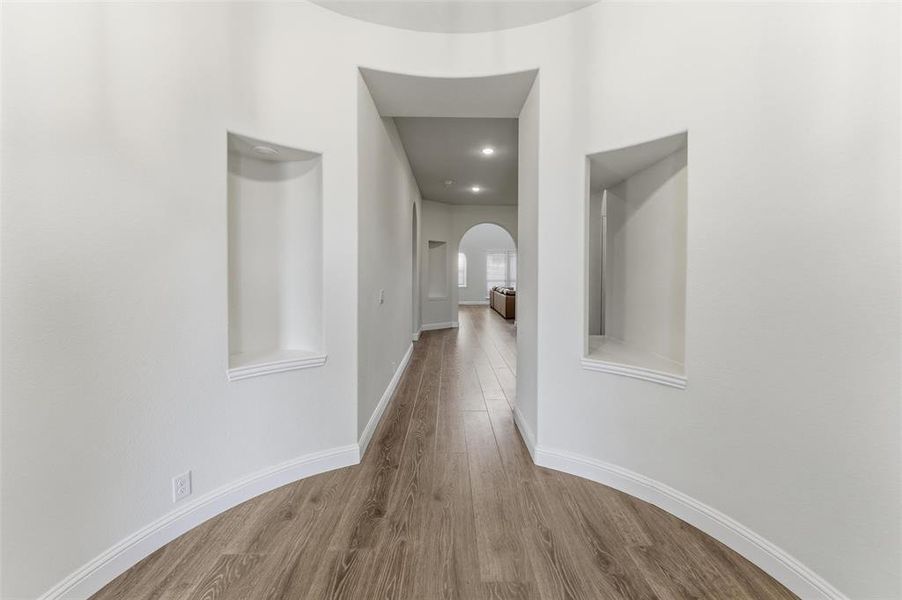 Corridor featuring arched walkways, wood finished floors, and recessed lighting