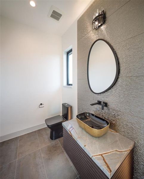 Third floor half bath with elegant built-in vanity, floating sink, framed mirror, wall sconce and exquisite porcelain backsplash