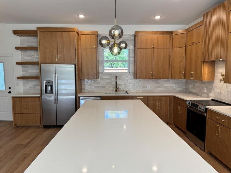 Kitchen featuring stainless steel appliances, sink, dark hardwood / wood-style floors, hanging light fixtures, and decorative backsplash