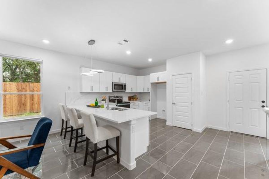 Kitchen featuring a breakfast bar area, white cabinets, stainless steel appliances, hanging light fixtures, and a peninsula Kitchen featuring a breakfast bar area, white cabinets, stainless steel appliances, hanging light fixtures, and a peninsula