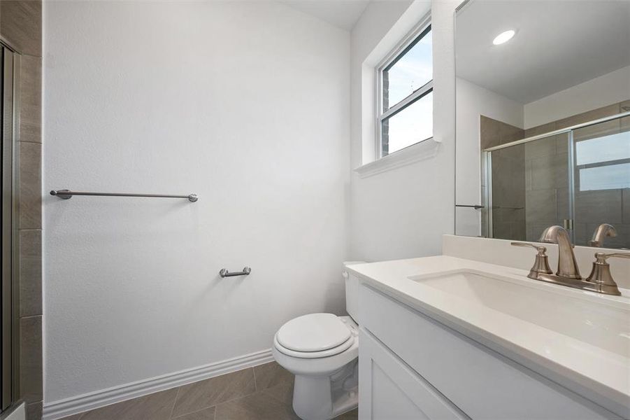 Full bath with a shower stall, vanity, and dark tile patterned flooring Full bath with a shower stall, vanity, and dark tile patterned flooring