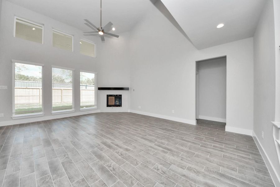 Welcome family and guests to your charming living room! With its high ceilings, recessed lighting, ceiling fan, custom paint, beautiful flooring, and large windows that let in abundant natural light, this room is perfect for gatherings.