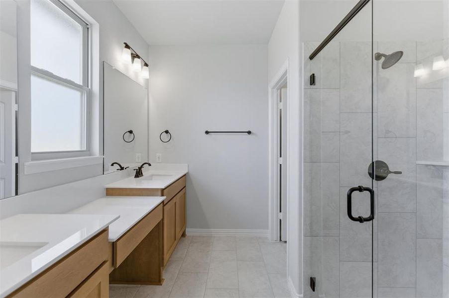 Full bathroom featuring double vanity, a shower stall, and light tile patterned floors