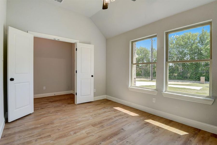 Unfurnished bedroom featuring ceiling fan, light hardwood / wood-style flooring, and vaulted ceiling