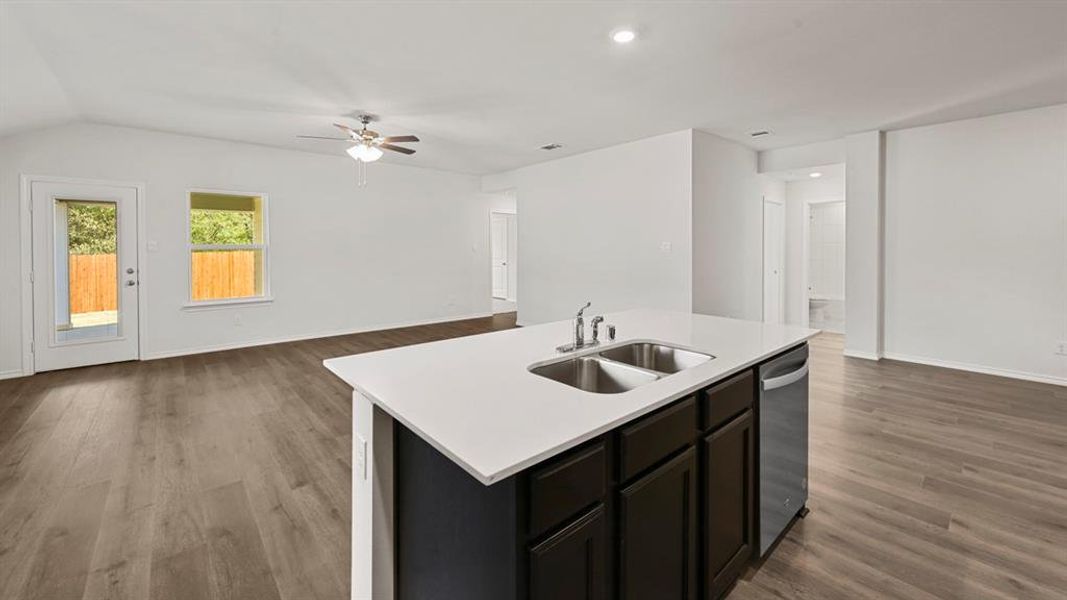 Kitchen island with a double basin sink, white countertop, and dark cabinetry Kitchen island with a double basin sink, white countertop, and dark cabinetry