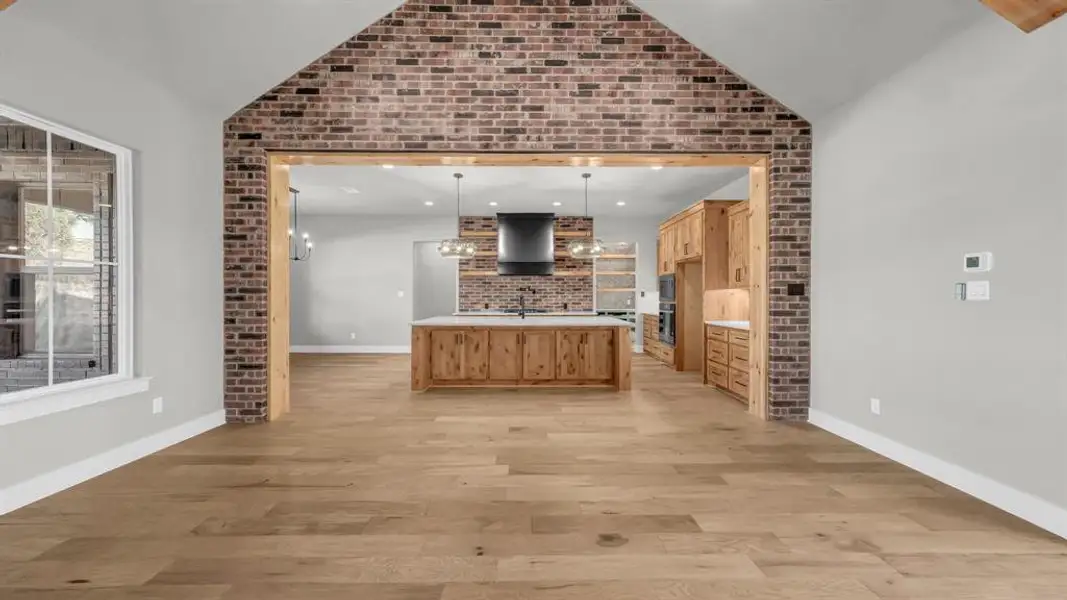 Expansive living area with wood-finish flooring and vaulted ceiling Expansive living area with wood-finish flooring and vaulted ceiling