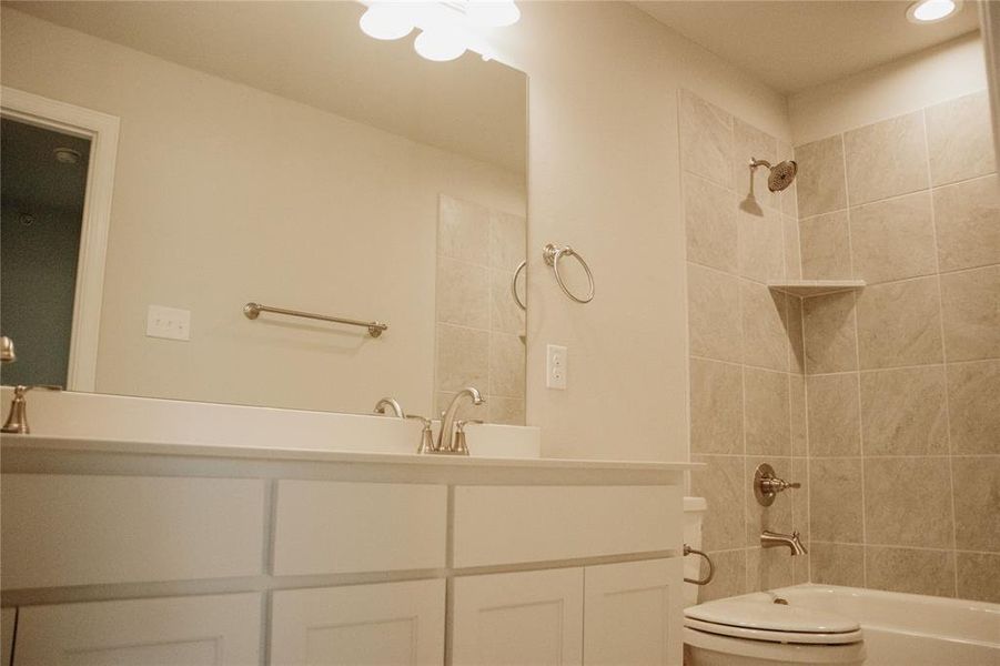 Full bathroom with vanity, tiled shower / bath combo, and toilet