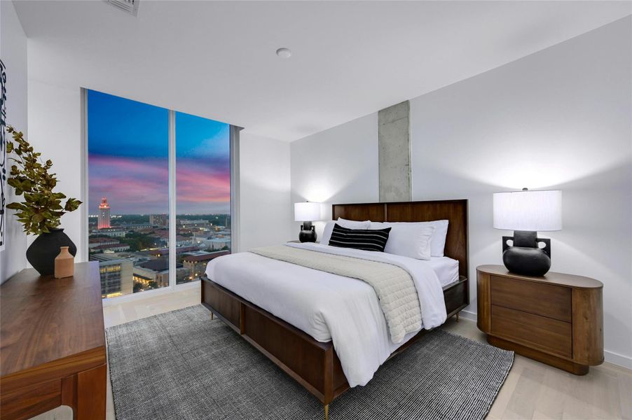 Step into this sleek and contemporary bedroom featuring floor-to-ceiling windows that frame spectacular views of the UT Tower (Photo from previous model Residence No. 2104 on lower level)