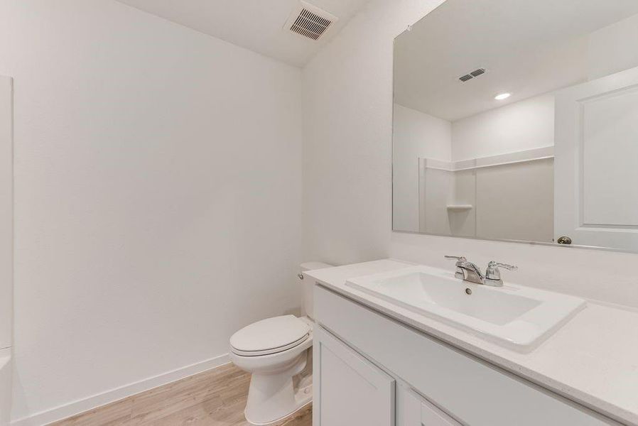 Bathroom featuring visible vents, toilet, baseboards, and wood finished floors