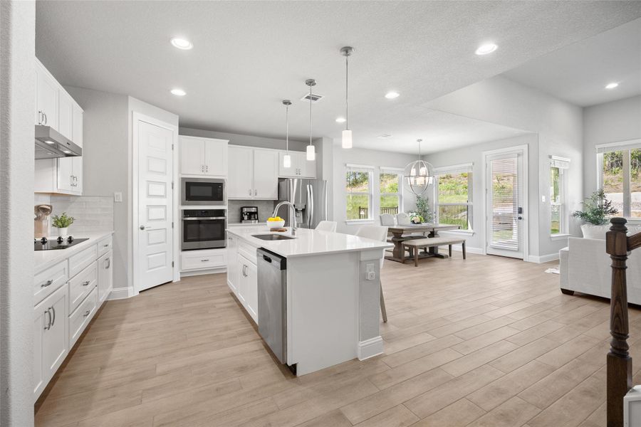 The kitchen flows into the dining and living areas through an open layout, enhancing the sense of space and connection throughout the home.