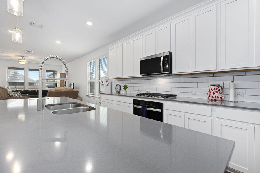A streamlined kitchen island with integrated sink overlooks an inviting living space, perfect for entertaining.