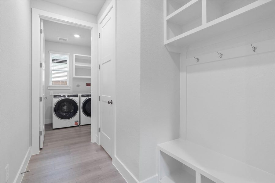 Functional mudroom area features a custom built-in bench with cubbies, leading directly into the laundry room. Functional mudroom area features a custom built-in bench with cubbies, leading directly into the laundry room.