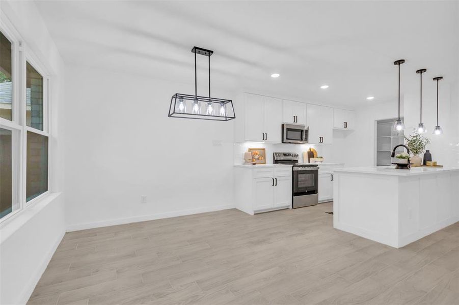 Kitchen featuring appliances with stainless steel finishes, recessed lighting, light countertops, light wood-style flooring, and white cabinetry