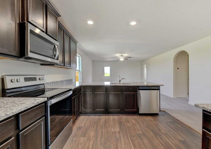 Frio kitchen with granite counters, stainless steel appliances and brown cabinetry