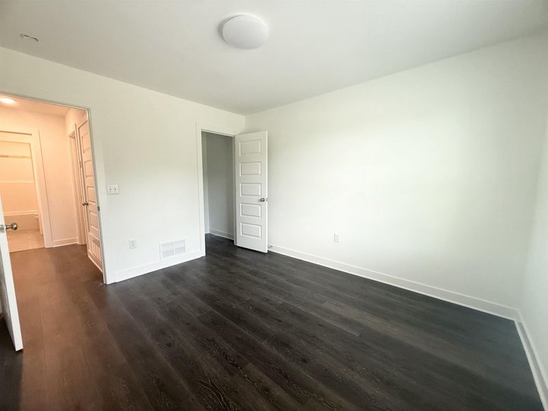 Unfurnished bedroom with dark wood-type flooring and baseboards