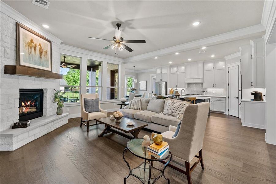 Living room with stone fireplace crown molding, a fireplace, and dark wood flooring!