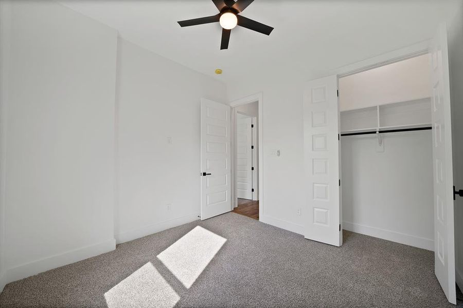 Unfurnished bedroom with light colored carpet, a ceiling fan, and a closet Unfurnished bedroom with light colored carpet, a ceiling fan, and a closet