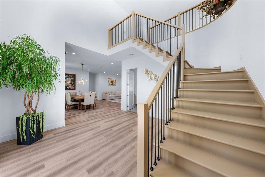 Stairway featuring wood finished floors, a high ceiling, and recessed lighting Stairway featuring wood finished floors, a high ceiling, and recessed lighting