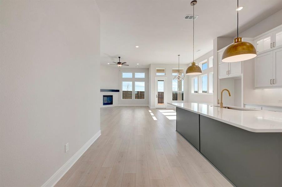 Kitchen, pendant lighting, two tone cabinetry, light wood-type flooring, and open floor plan Kitchen, pendant lighting, two tone cabinetry, light wood-type flooring, and open floor plan