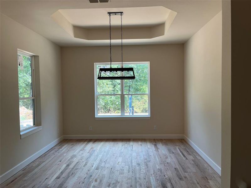 Dining area with trey ceiling, hardwood floors, decorative lighting. Dining area with trey ceiling, hardwood floors, decorative lighting.