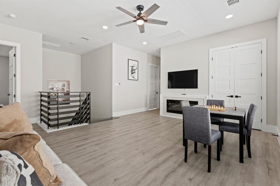 Dining space featuring a glass covered fireplace, recessed lighting, light wood finished floors, and ceiling fan