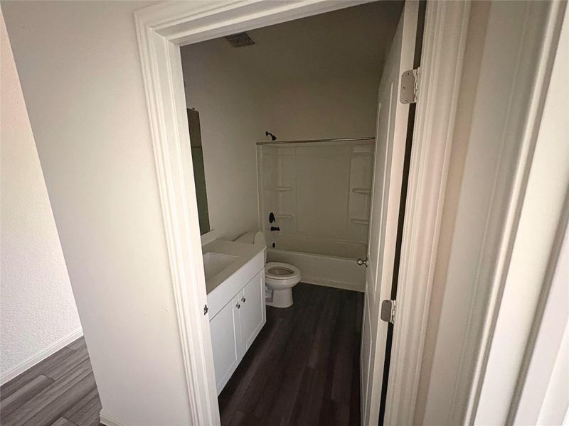 Full bathroom with vanity, bathtub / shower combination, and dark wood-style flooring Full bathroom with vanity, bathtub / shower combination, and dark wood-style flooring