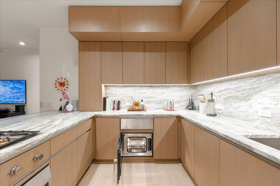 A Gaggenau® built-in steam oven seamlessly integrated into custom Rhode Partners cabinetry, paired with 3cm Fantasy Brown marble counters and backsplash. This chef-caliber feature supports precise, healthy cooking and reinforces the kitchen’s Omakase-inspired, penthouse-level design.