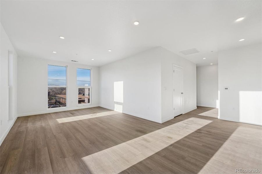 Bright open-concept living area with wide-plank flooring, abundant natural light, and a modern kitchen featuring stainless steel appliances and sleek cabinetry.