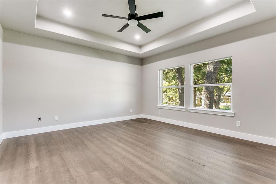 Spare room with a raised ceiling, wood finished floors, ceiling fan, and recessed lighting