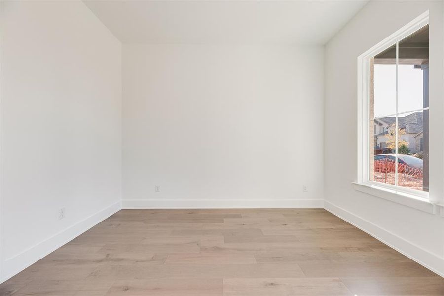 Spare room featuring light wood-type flooring and baseboards