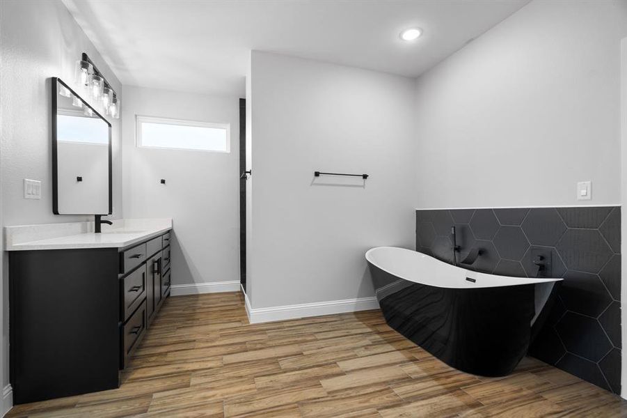 Bathroom featuring a bath, vanity, and wood-type flooring