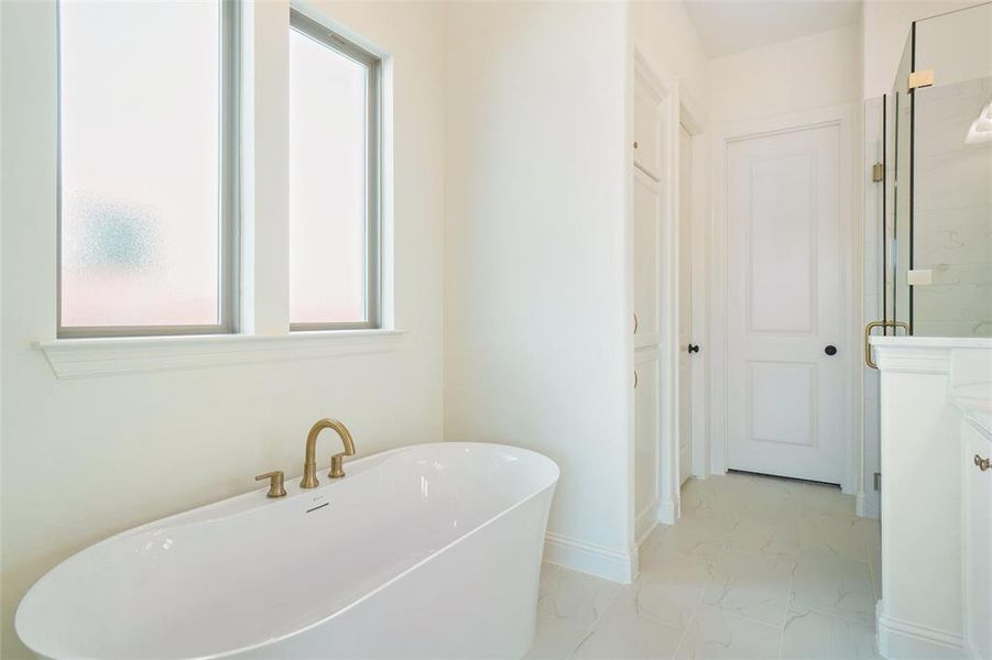 Full bath with marble look tile flooring, a soaking tub, and vanity Full bath with marble look tile flooring, a soaking tub, and vanity