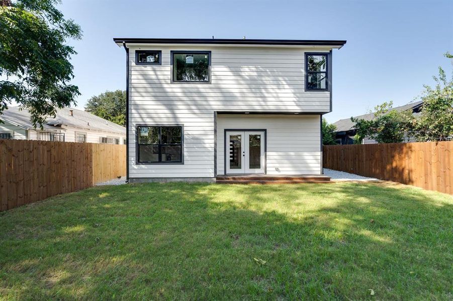 Rear view of house featuring a lawn and french doors