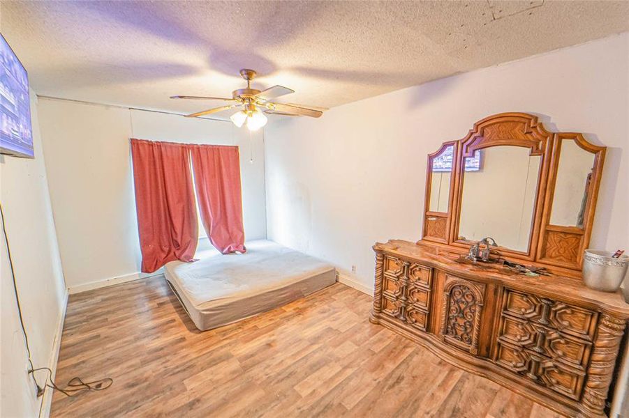 Bedroom featuring a textured ceiling, light wood-style floors, and a ceiling fan Bedroom featuring a textured ceiling, light wood-style floors, and a ceiling fan