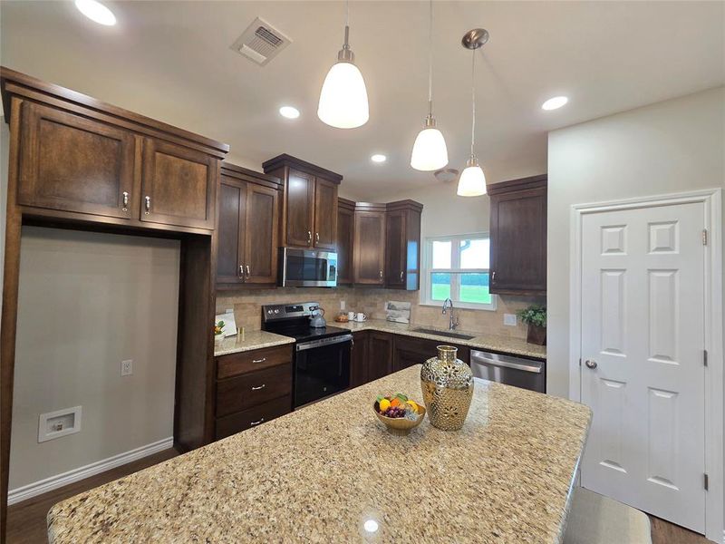Kitchen featuring stainless steel appliances, dark brown cabinets, decorative backsplash, and recessed lighting Kitchen featuring stainless steel appliances, dark brown cabinets, decorative backsplash, and recessed lighting