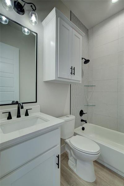 Full bathroom featuring hardwood / wood-style floors, vanity, toilet, and tiled shower / bath combo