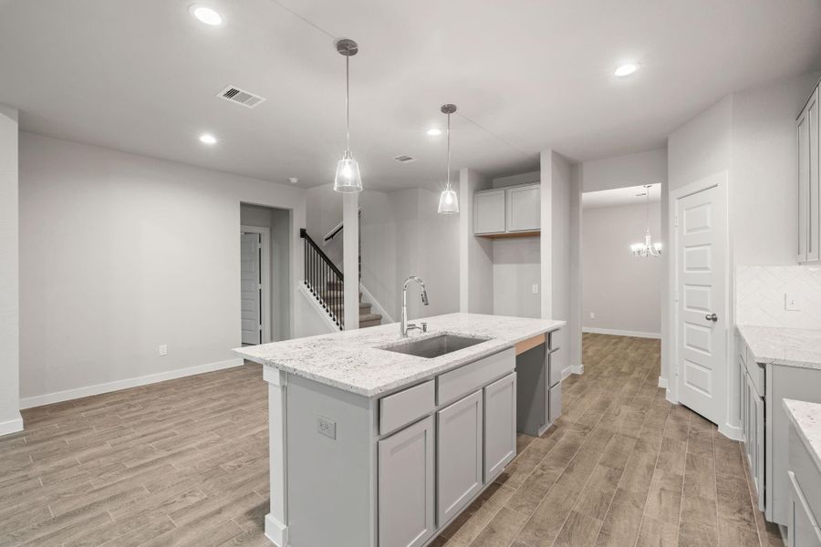 Discover another perspective of this stunning kitchen, generously appointed with an abundance of counter space. Sample photo of completed home with similar floor plan. As-built interior colors and selections may vary.