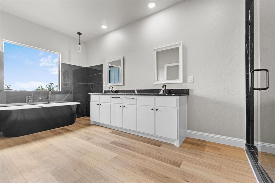 Bathroom featuring double vanity, light wood-style flooring, and a freestanding bath