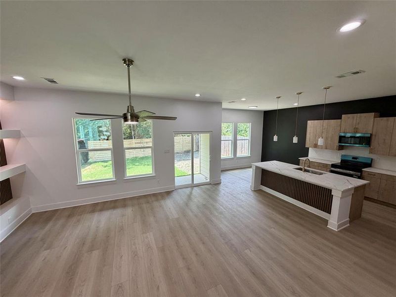 Open-concept living space featuring wood-finish flooring, recessed lighting, and a contemporary ceiling fan Open-concept living space featuring wood-finish flooring, recessed lighting, and a contemporary ceiling fan
