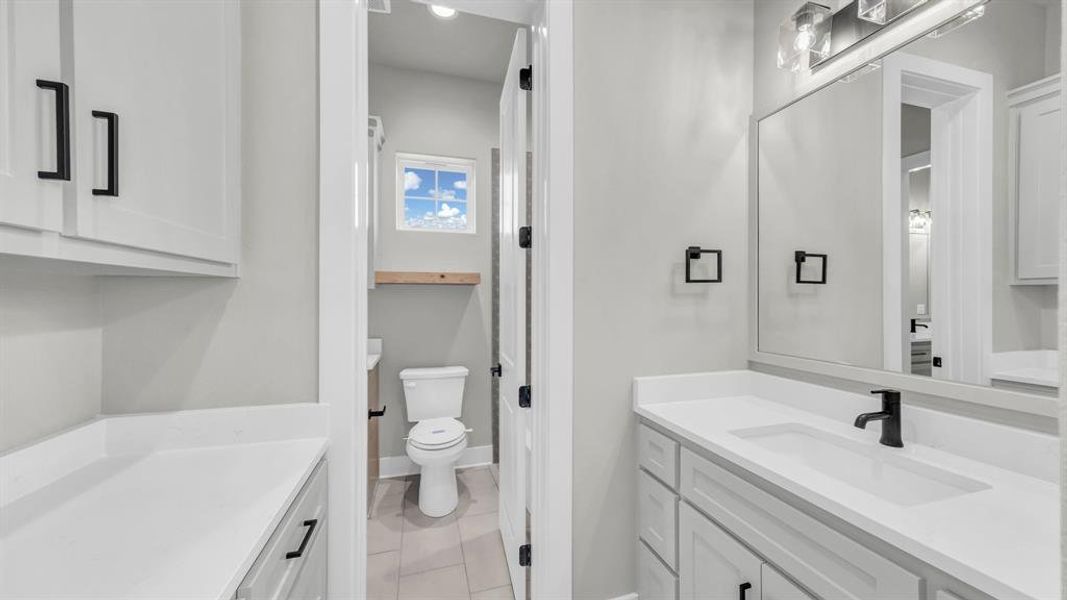 Bathroom vanity featuring white cabinetry, a white countertop, and a rectangular undermount sink with a matte black faucet