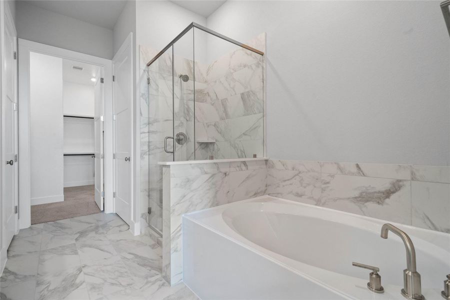 Indulge in relaxation within this spa-inspired primary bathroom, offering both a quick shower and a tranquil soaking experience. The walk-in shower is glass enclosed with modern tile walls and brushed nickel finishes.