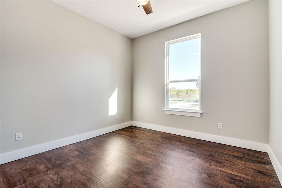 Empty room featuring ceiling fan and dark hardwood / wood-style flooring