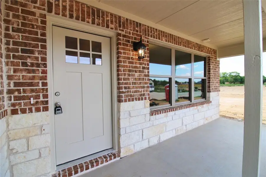 Property entrance featuring brick siding and covered porch