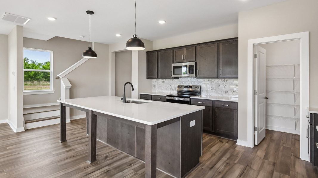 Kitchen with dark cabinetry, quartz countertops, pendant lighting, and tile backsplash