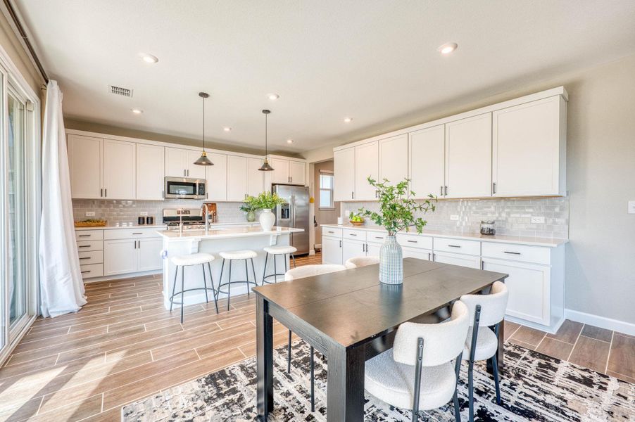 An open kitchen and dining area features recessed lighting, extensive cabinetry, and wood-look tile flooring. An open kitchen and dining area features recessed lighting, extensive cabinetry, and wood-look tile flooring.