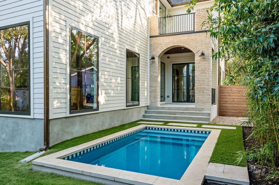An inviting private pool and artificial turf are perfectly situated behind this refined brick and siding residence.