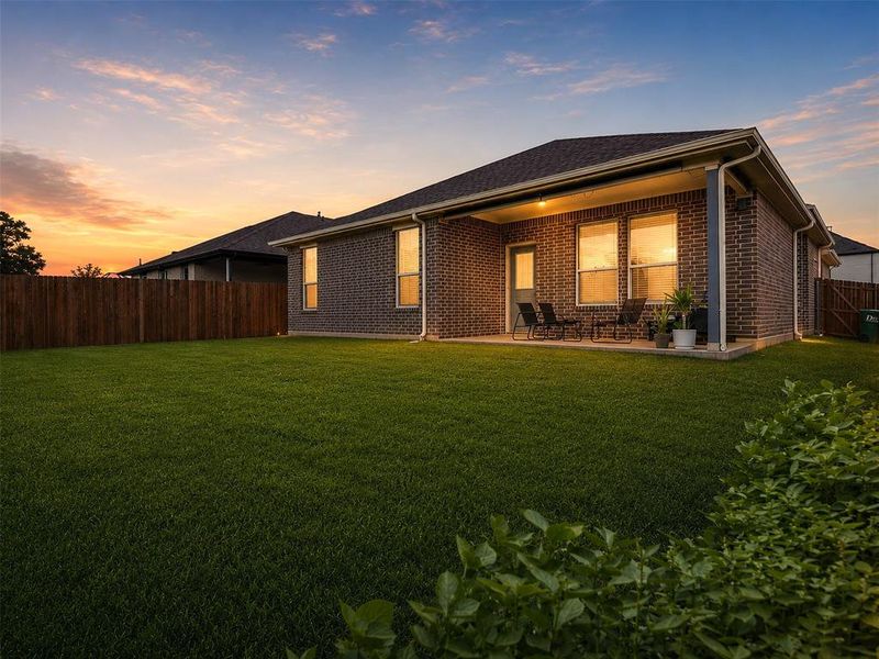 Spacious backyard featuring a covered patio, dark brick exterior, and full privacy fencing Spacious backyard featuring a covered patio, dark brick exterior, and full privacy fencing