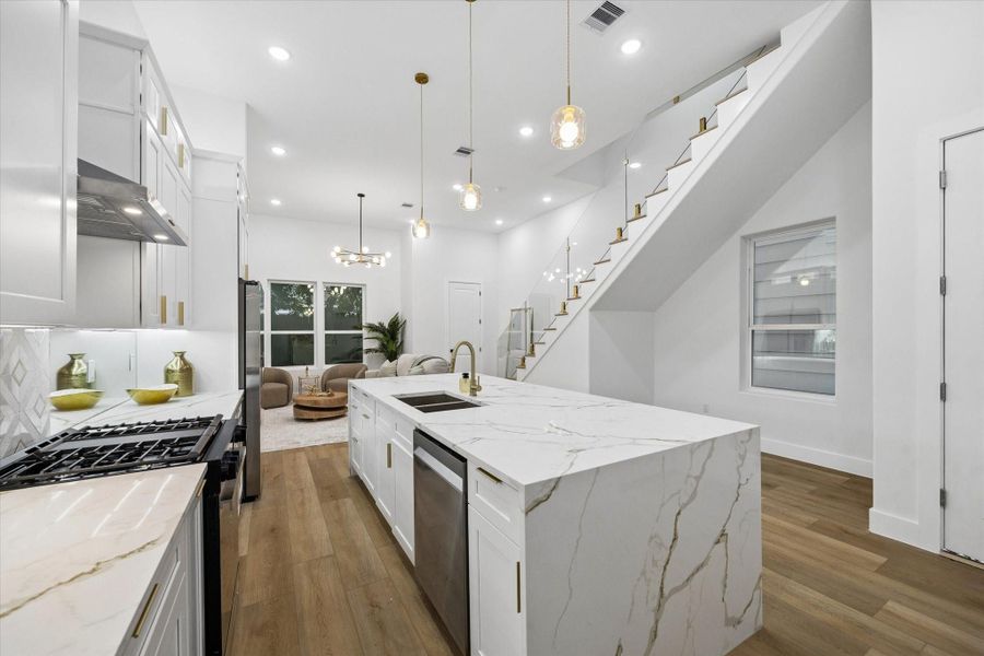 This modern home features an open-concept kitchen and living area with high ceilings and elegant finishes. The kitchen boasts a large marble island, stainless steel appliances, and stylish pendant lighting. A sleek staircase leads to the upper level, enhancing the contemporary design. This modern home features an open-concept kitchen and living area with high ceilings and elegant finishes. The kitchen boasts a large marble island, stainless steel appliances, and stylish pendant lighting. A sleek staircase leads to the upper level, enhancing the contemporary design.